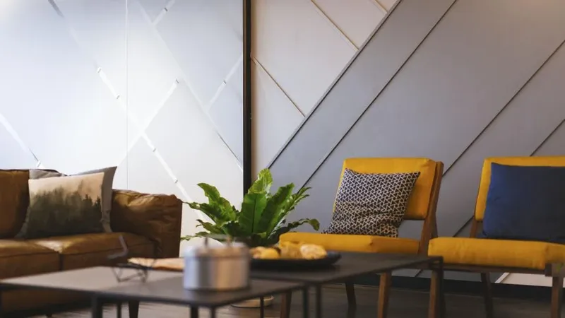 A living room with mustard armchairs, a low table and a leafy plant